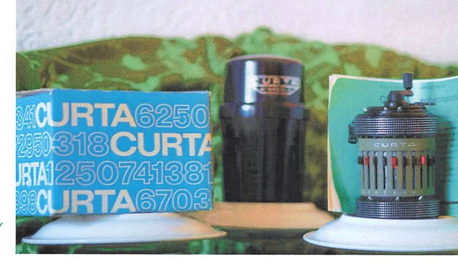 A CURTA mechanical calculator displayed beside its boxed instruction manual.